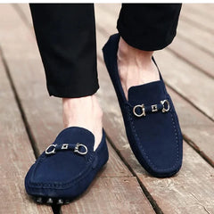Navy suede loafers with silver buckle hardware worn with dark pants