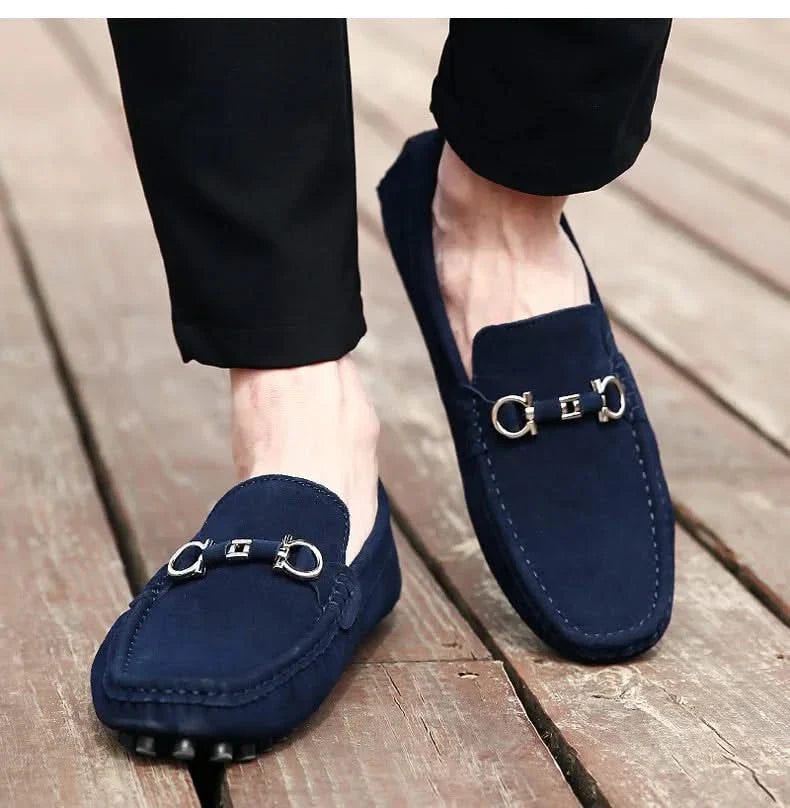 Navy suede loafers with silver buckle hardware worn with dark pants