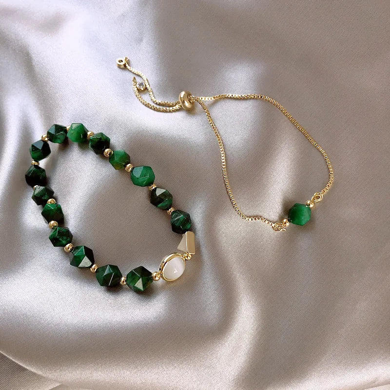 Two gold-tone bracelets with dark green faceted beads and pearl-style centerpiece