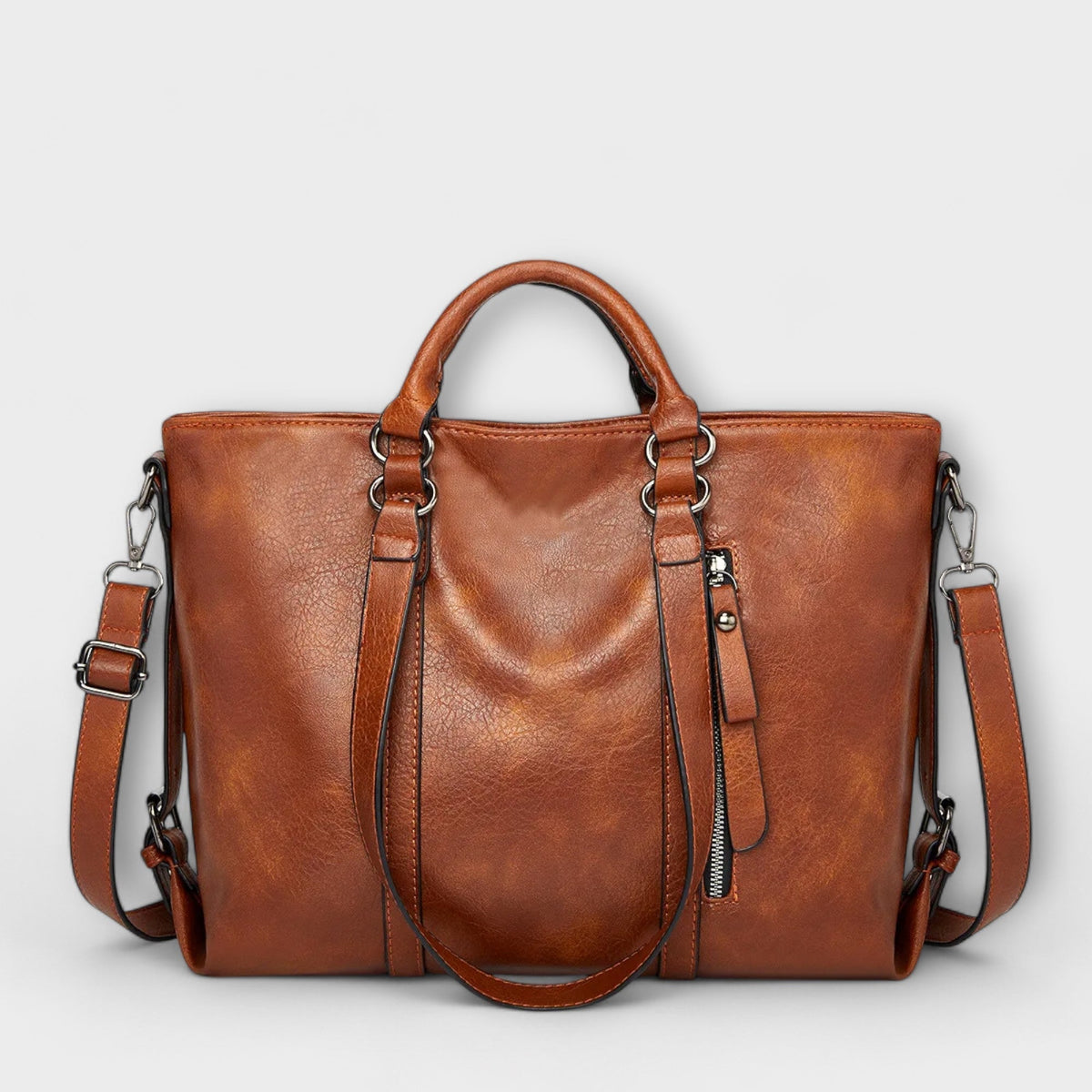 Brown large leather handbag with top handles, side straps, and zip pocket detail