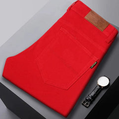 Red denim jeans folded flat, visible front pocket and brown leather logo patch