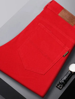 Red denim jeans folded flat, visible front pocket and brown leather logo patch