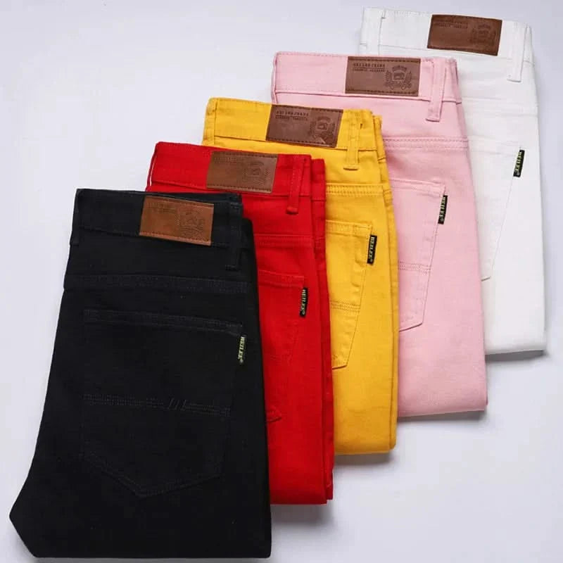 Assorted colored denim jeans folded together, including black, red, yellow, and pink
