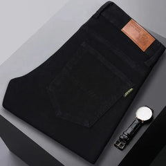 Black denim jeans folded flat, visible front pocket and brown leather logo patch