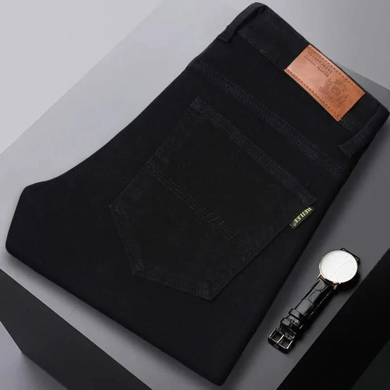 Black denim jeans folded flat, visible front pocket and brown leather logo patch