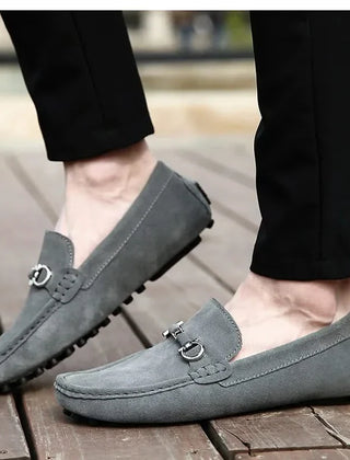 Gray suede loafers with silver buckle hardware and rubber tread sole