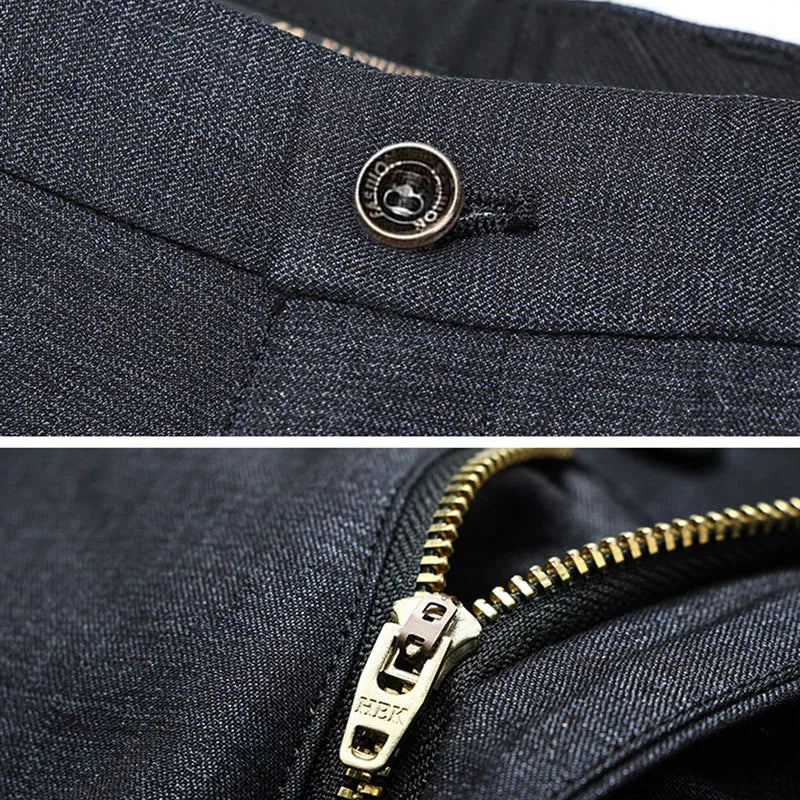Dark textured trouser fabric detail with metal button and zipper closure.