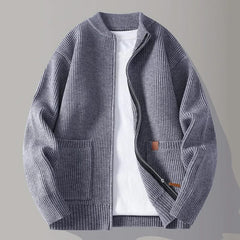 Slate blue rib knit zip-up jacket with stand collar, front pockets, and tan logo patch