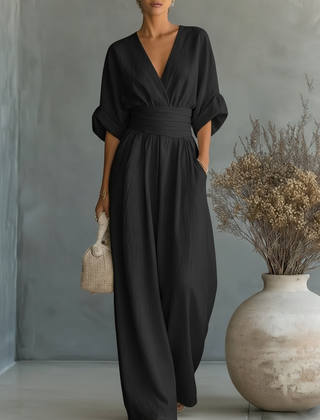 Black V-neck high-waisted jumpsuit with wrap-style top and flowing wide-leg fit
