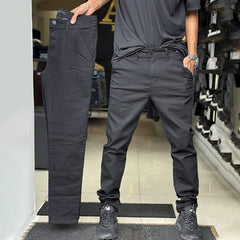 Dark grey slim trousers with tapered legs, button waist, and side pockets
