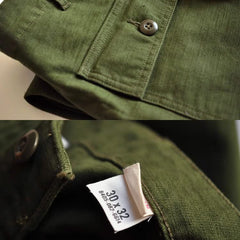 Olive green fatigue pants fabric close-up with metal button and branded care label
