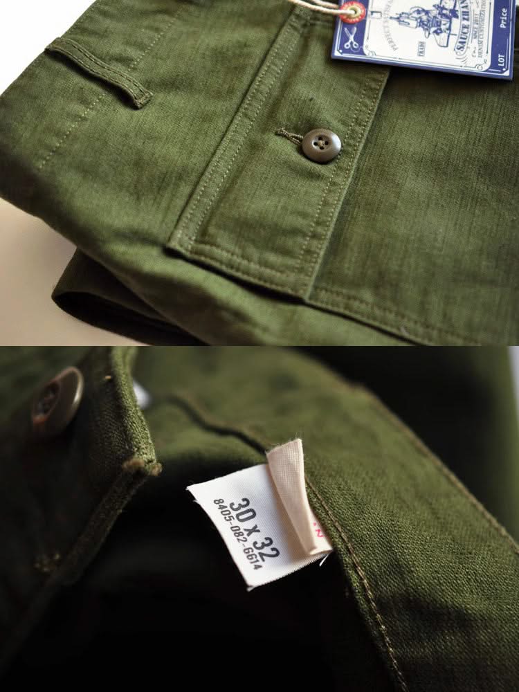 Olive green fatigue pants fabric close-up with metal button and branded care label