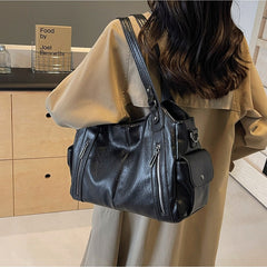 Black leather shoulder handbag with dual handles, front zip pockets, and attached strap