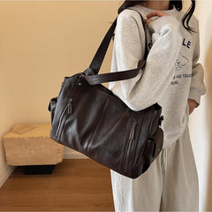 Dark brown leather handbag worn on shoulder with dual handles and zip front pockets