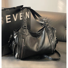 Black leather handbag with dual handles, front zippers, and shoulder strap