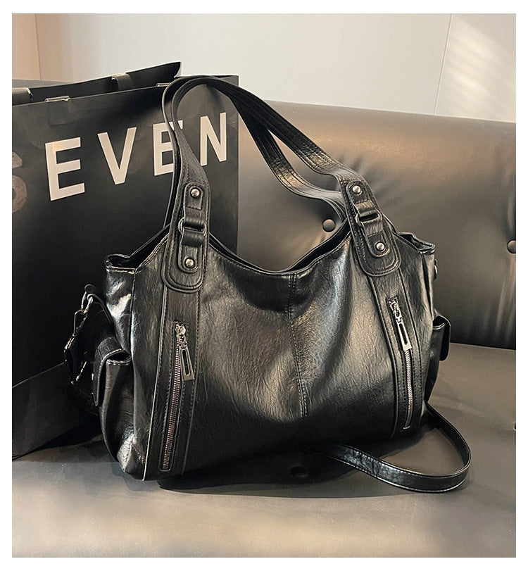 Black leather handbag with dual handles, front zippers, and shoulder strap