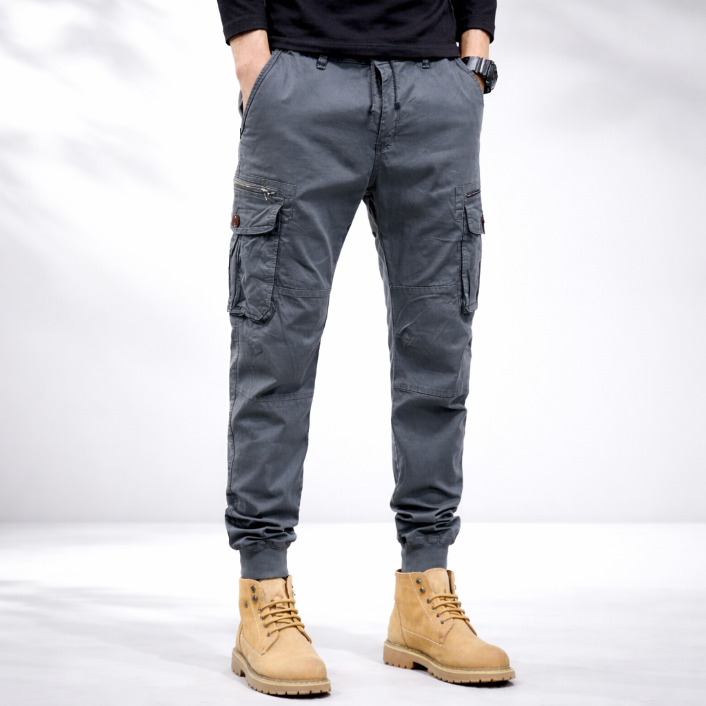 Dark grey cargo pants on model, drawstring waist, cuffed ankles, and cargo side pockets
