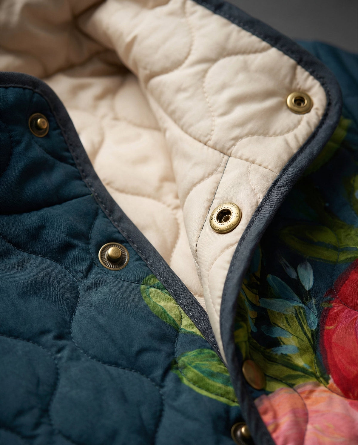 Amaya quilted jacket close-up: dark blue collar with brass buttons and beige lining
