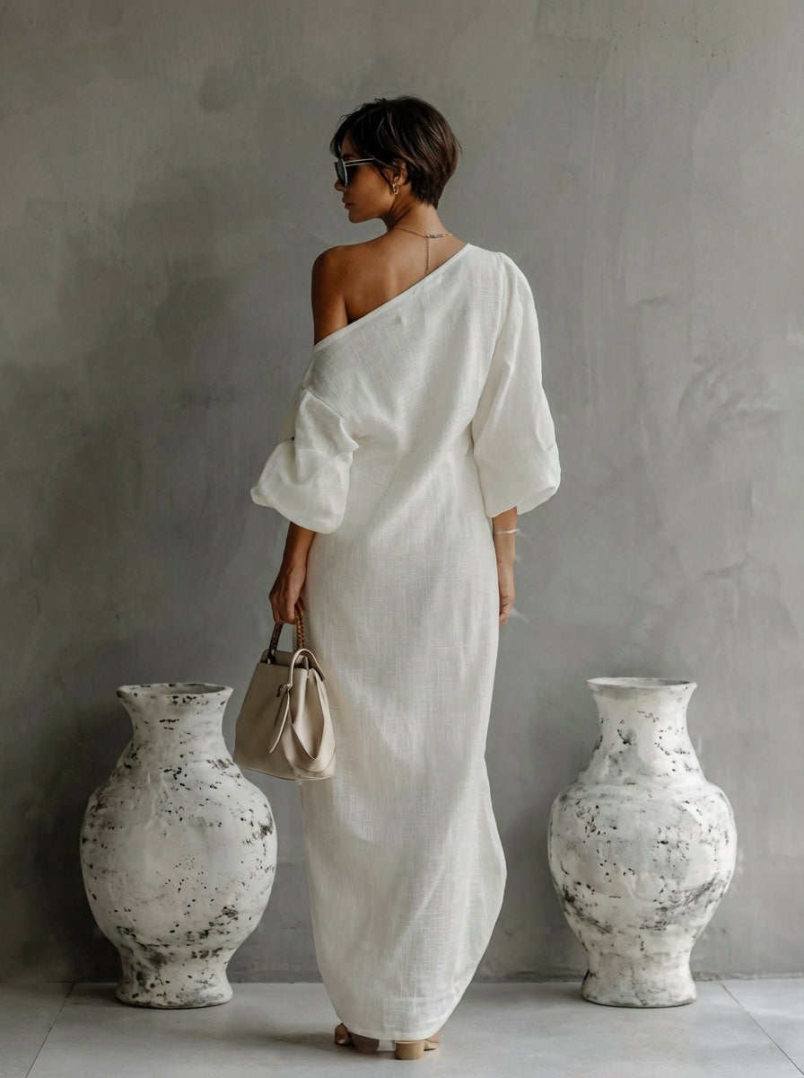 White one-shoulder maxi dress with draped sleeve detail and long column skirt