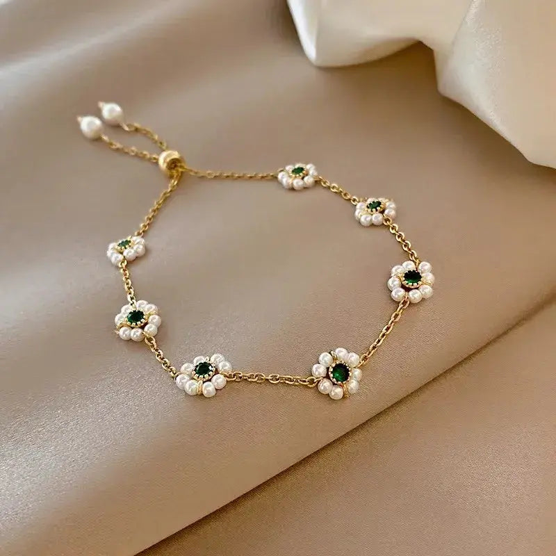 Daisy-inspired bracelet with gold chain, white pearl flower charms and green centers