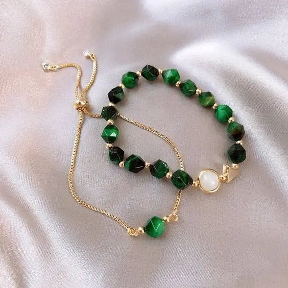 Gold-tone gem bracelet set with dark green faceted beads and round pearl-style charm