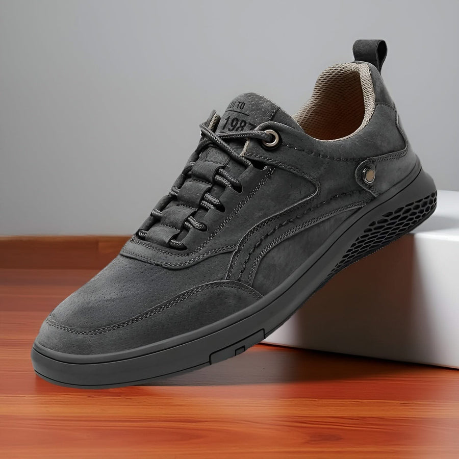 Grey suede lace-up sneakers with lace eyelets, stitched seams, and grippy outsole