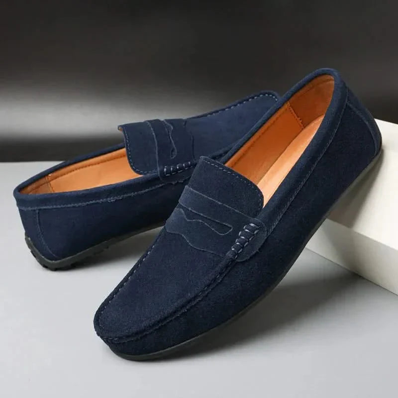 Suede loafers in navy with strap detail, moc stitching, and orange-brown lining